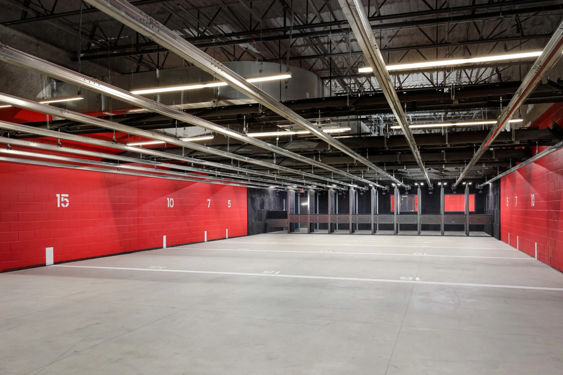 Empty indoor shooting range with red walls and concrete floor.