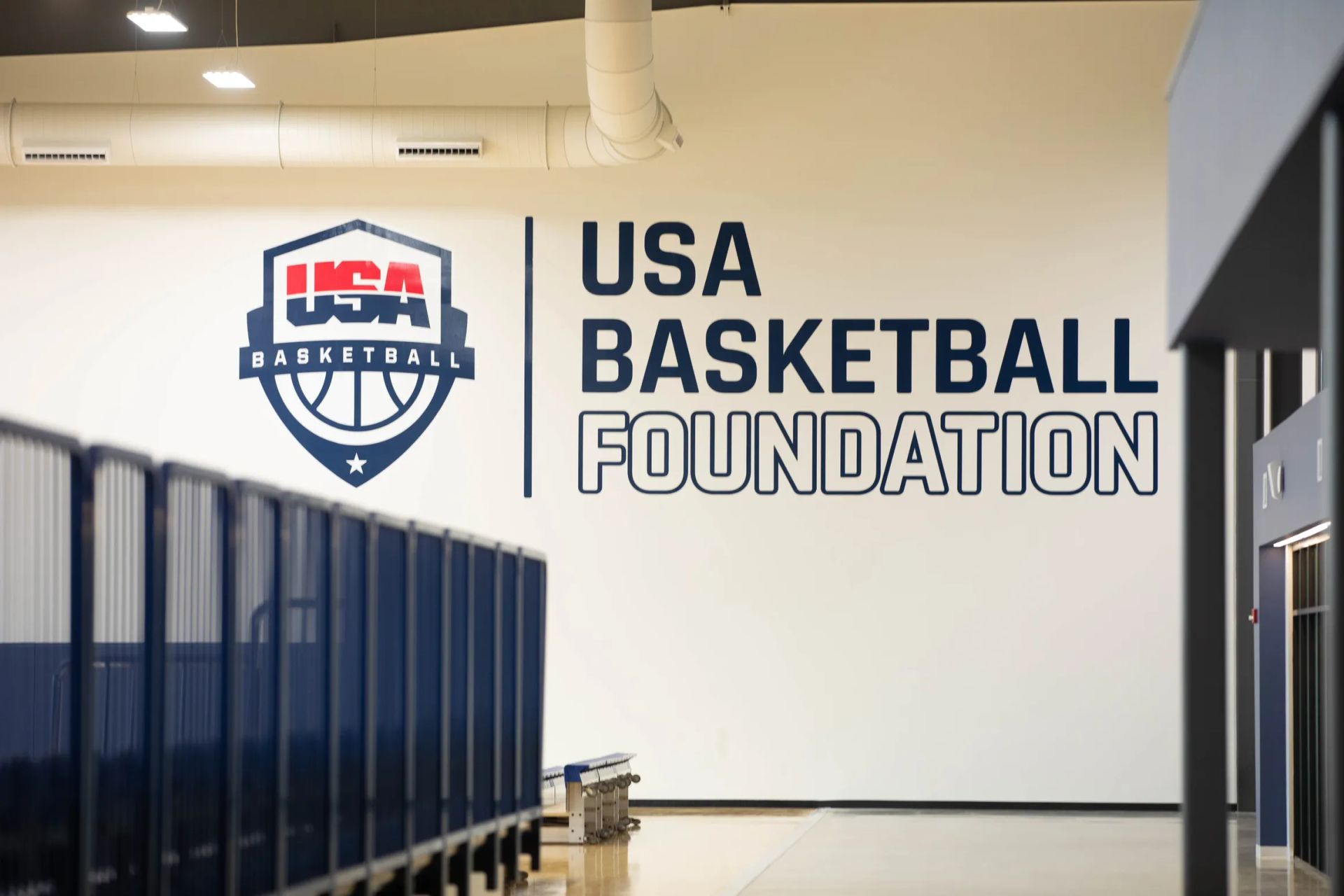 USA Basketball Foundation logo on a white wall in a basketball facility. Blue and white colors.
