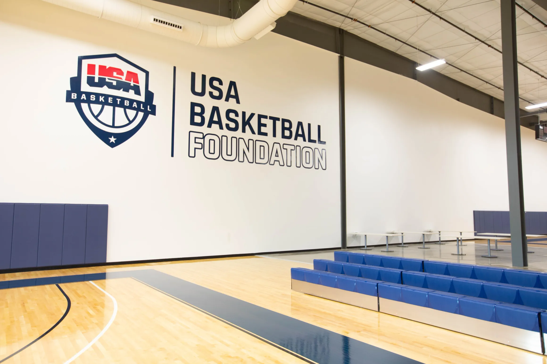 Basketball court with USA Basketball Foundation logo and blue padded seating.