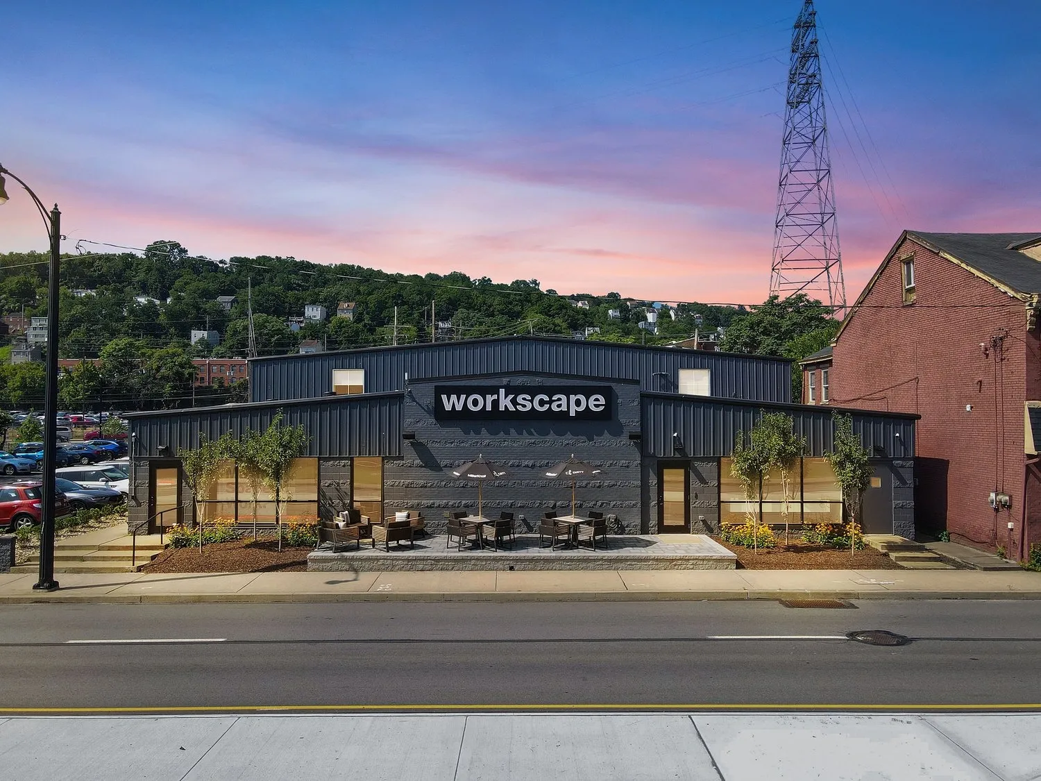 Exterior view of Workscape building with gray facade, outdoor seating, and colorful sky.