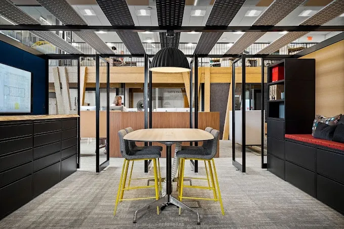 Modern office meeting area with table and chairs; a black and yellow color scheme is present.