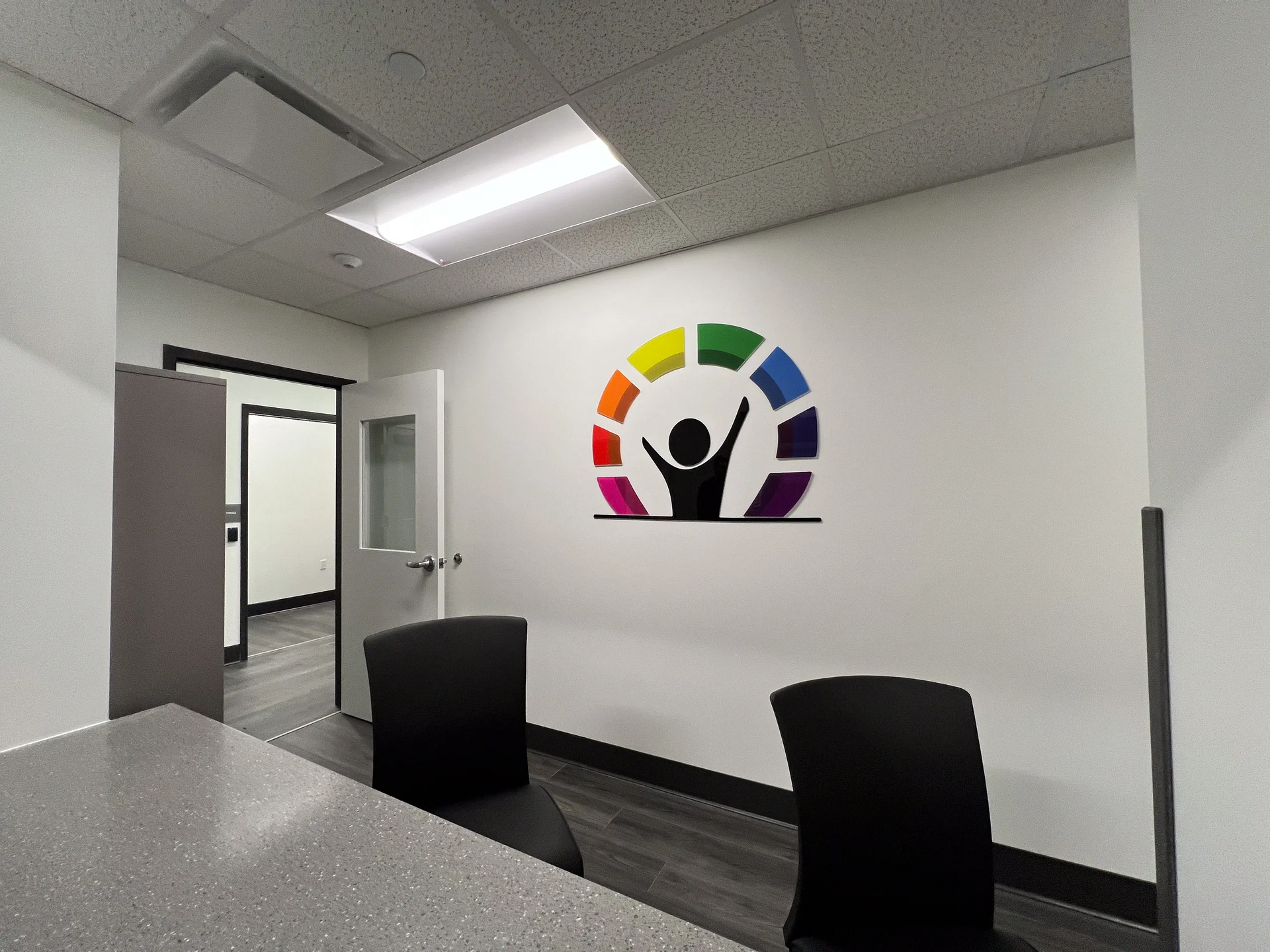Office interior with logo on the wall and two black chairs.