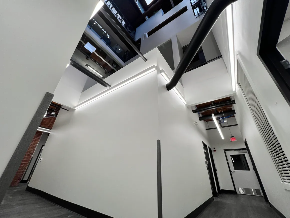 Interior hallway with white walls and black trim, leading to a door and looking up to other levels.