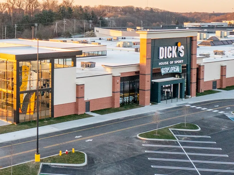 Exterior view of a Dick's House of Sport store with a climbing wall visible through large windows.