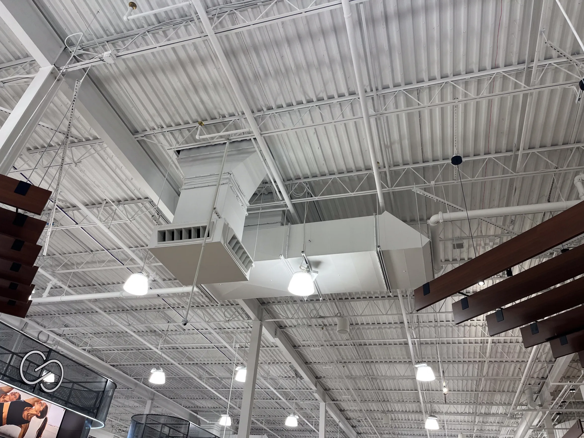 White ceiling with ventilation ductwork and light fixtures in a retail space.