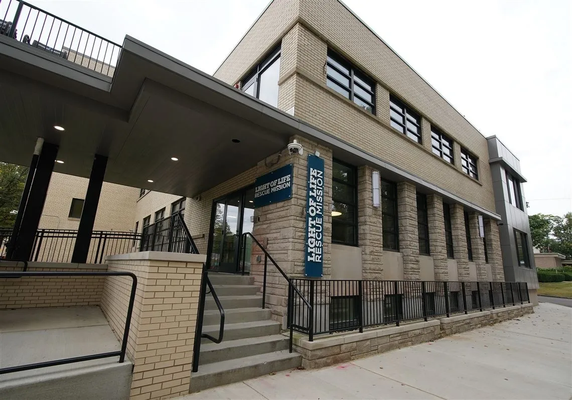 Brick office building with entrance stairs and a blue sign.
