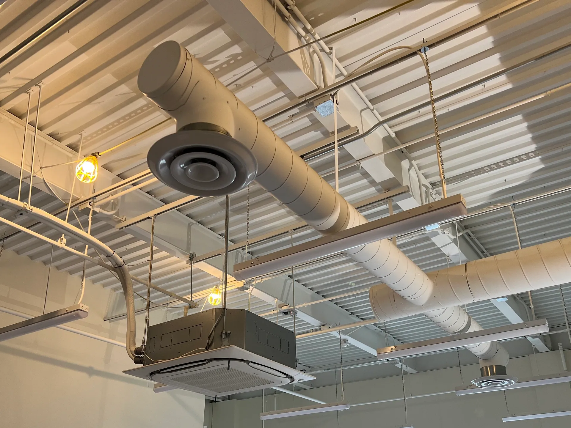 HVAC ceiling unit with ductwork and lighting in a commercial space.