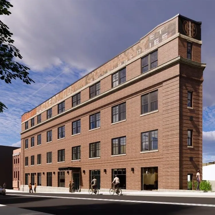 Brick building with storefronts, pedestrians, and cyclists on the street. Cloudy sky.