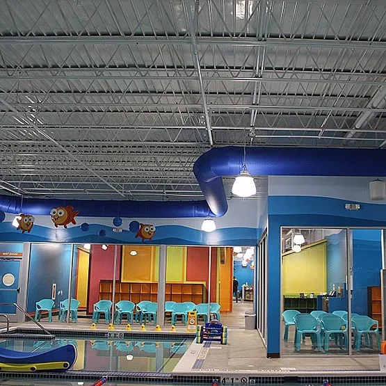 Indoor swimming pool area with blue, yellow and pink walls, and fish decorations.