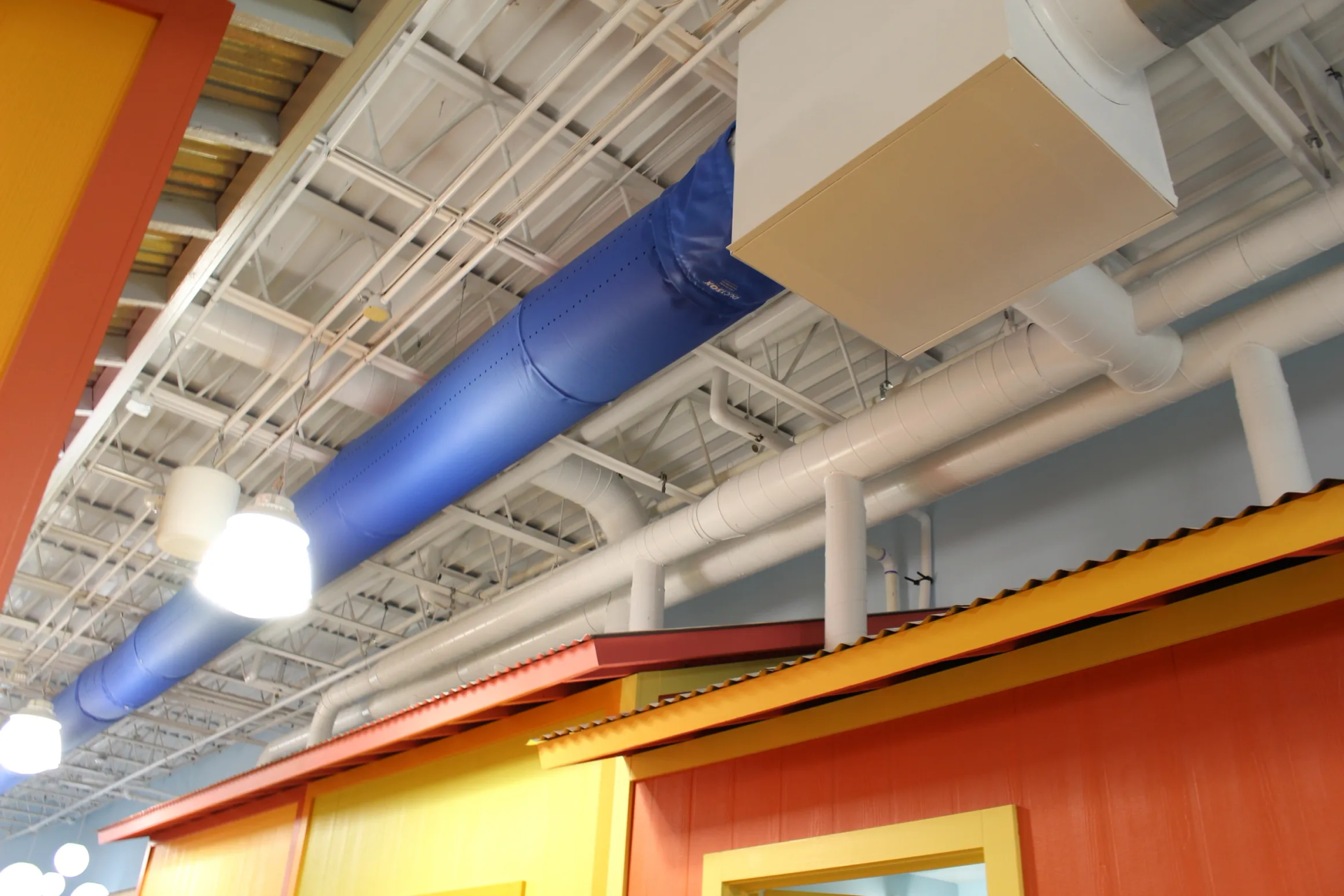 Brightly colored interior with ceiling pipes and a blue ventilation duct.