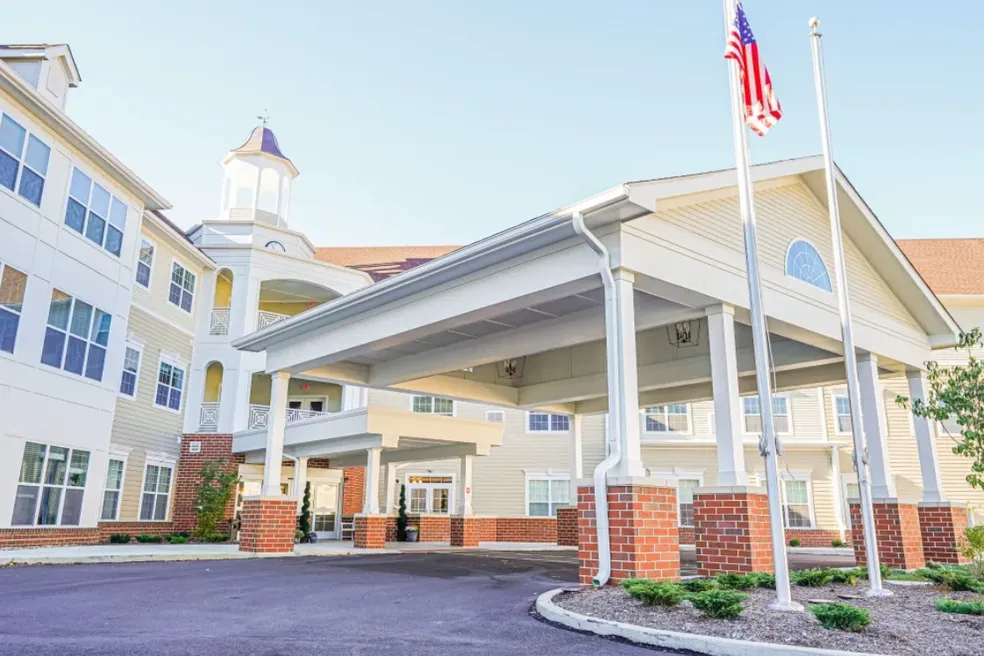 Cream-colored building with a covered entrance, brick columns, and US flag.