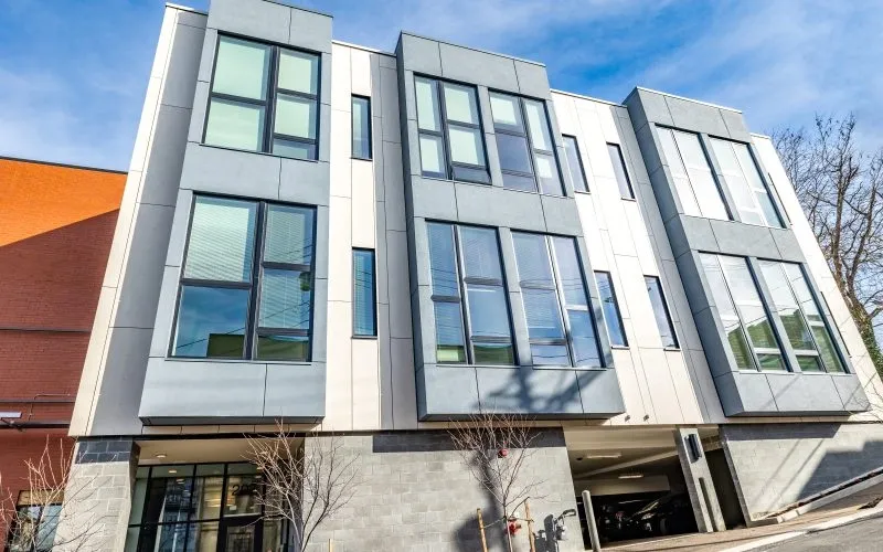 Modern multi-story building with large windows and a parking garage entrance.