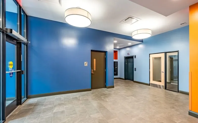 Entrance hall with blue walls, tile floor, elevator, and orange accent wall.