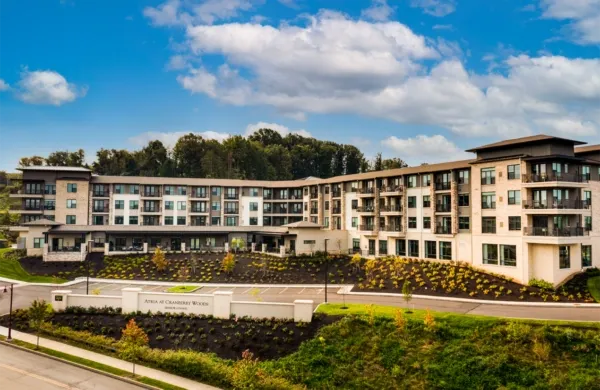 Large beige and white multi-story building on a hillside under a blue sky, with a sign in front.