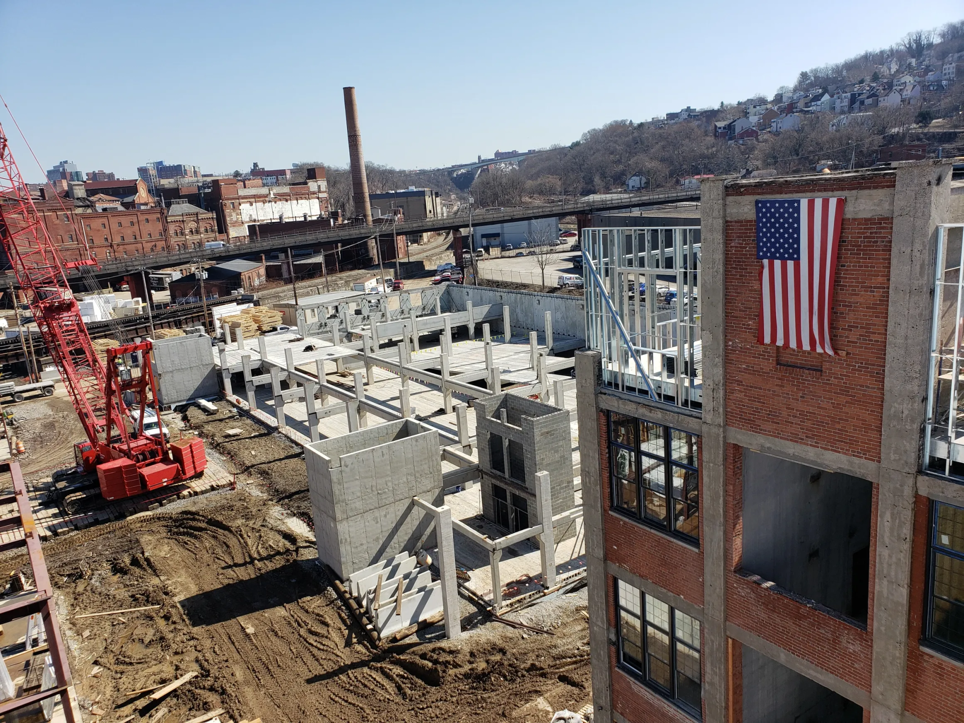 Construction site with a partially built brick building, crane, and American flag.