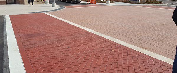 A person is standing on a red brick sidewalk.