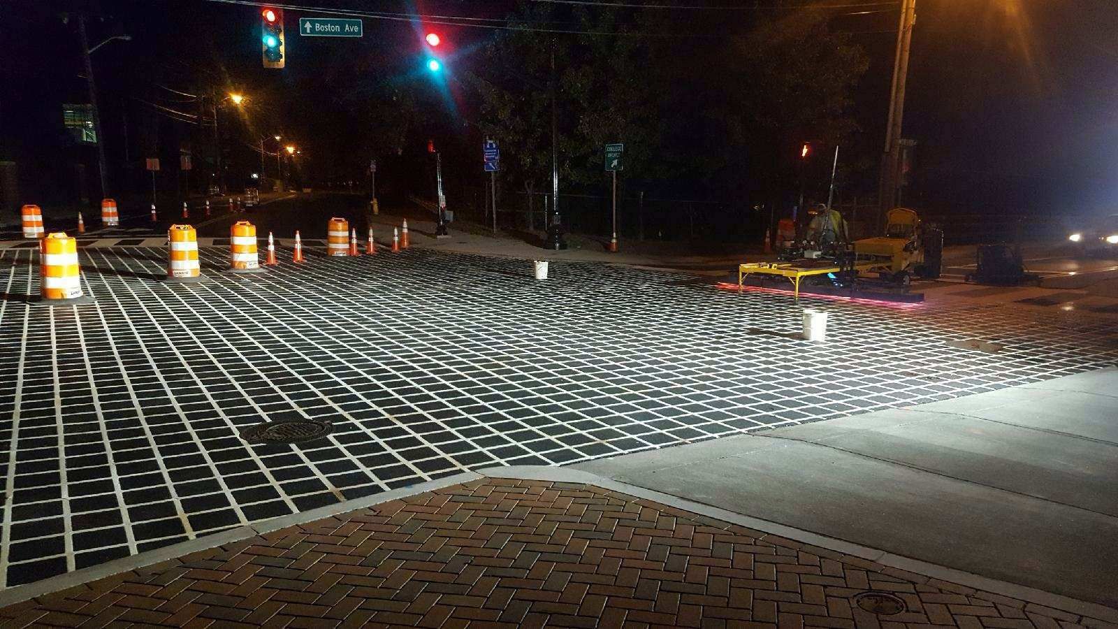 A brick intersection at night with a lot of bricks on the ground.