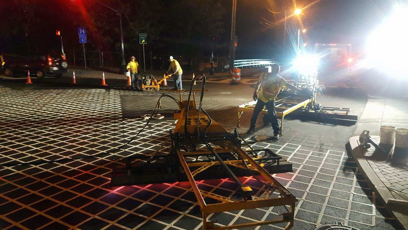 A man is standing next to a machine on a street at night.