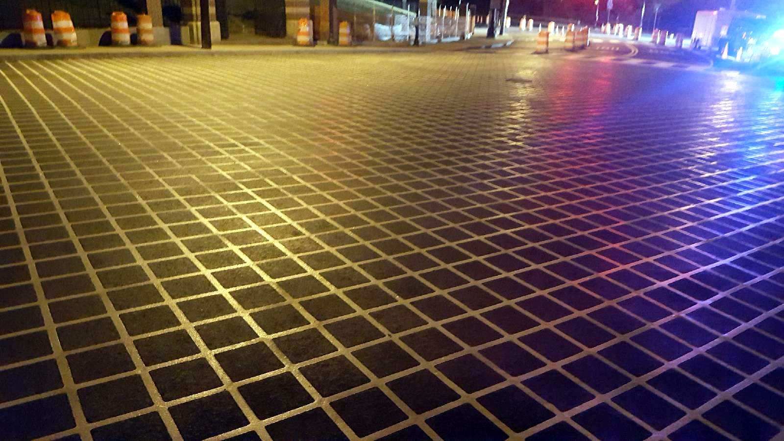 A brick pavement with a grid pattern is lit up at night.