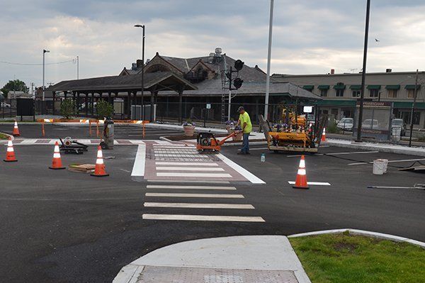 A group of construction workers are working on a crosswalk in a parking lot.