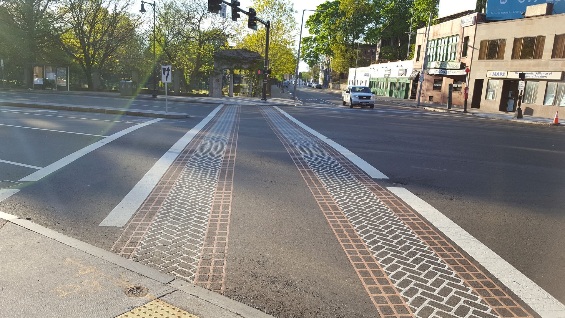 A busy intersection with a brick walkway and a white line on the road