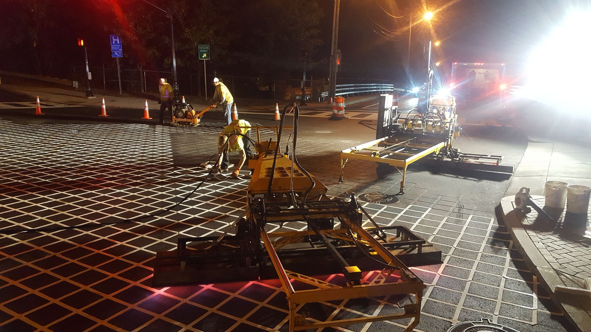 A group of construction workers are working on a street at night.