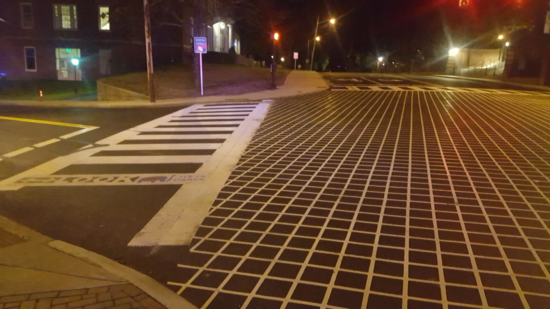 A crosswalk is painted on the side of the road at night.