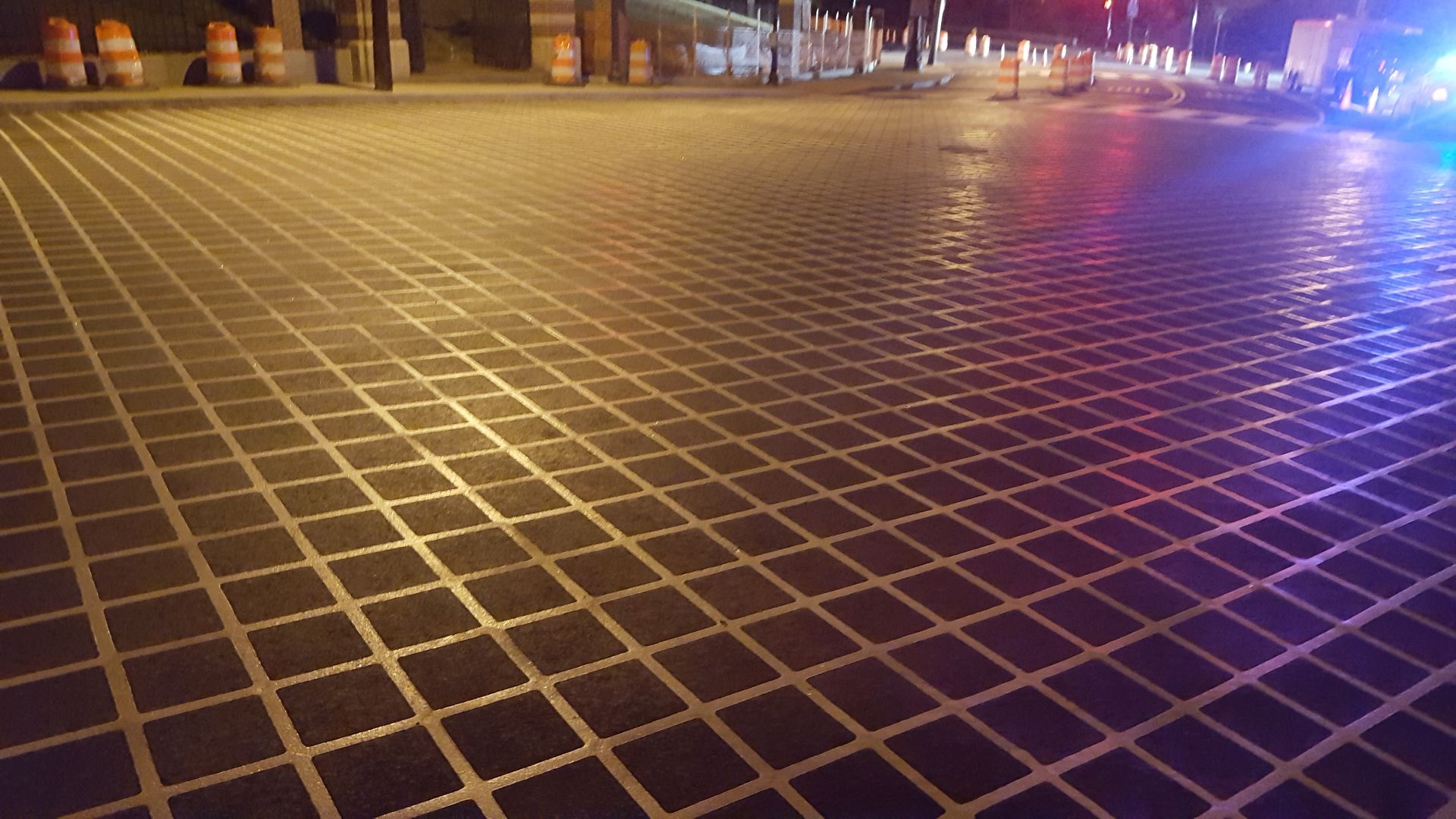 A brick pavement with a checkered pattern is lit up at night.