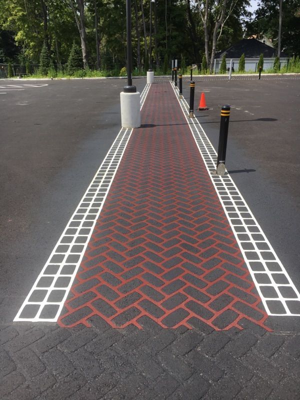 A brick walkway is painted in a parking lot
