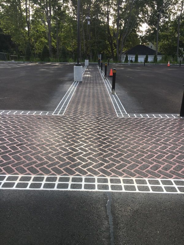 A brick walkway is painted on the side of a parking lot.