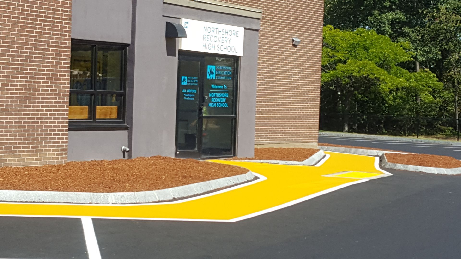 A yellow curb is painted on the side of a parking lot in front of a building.
