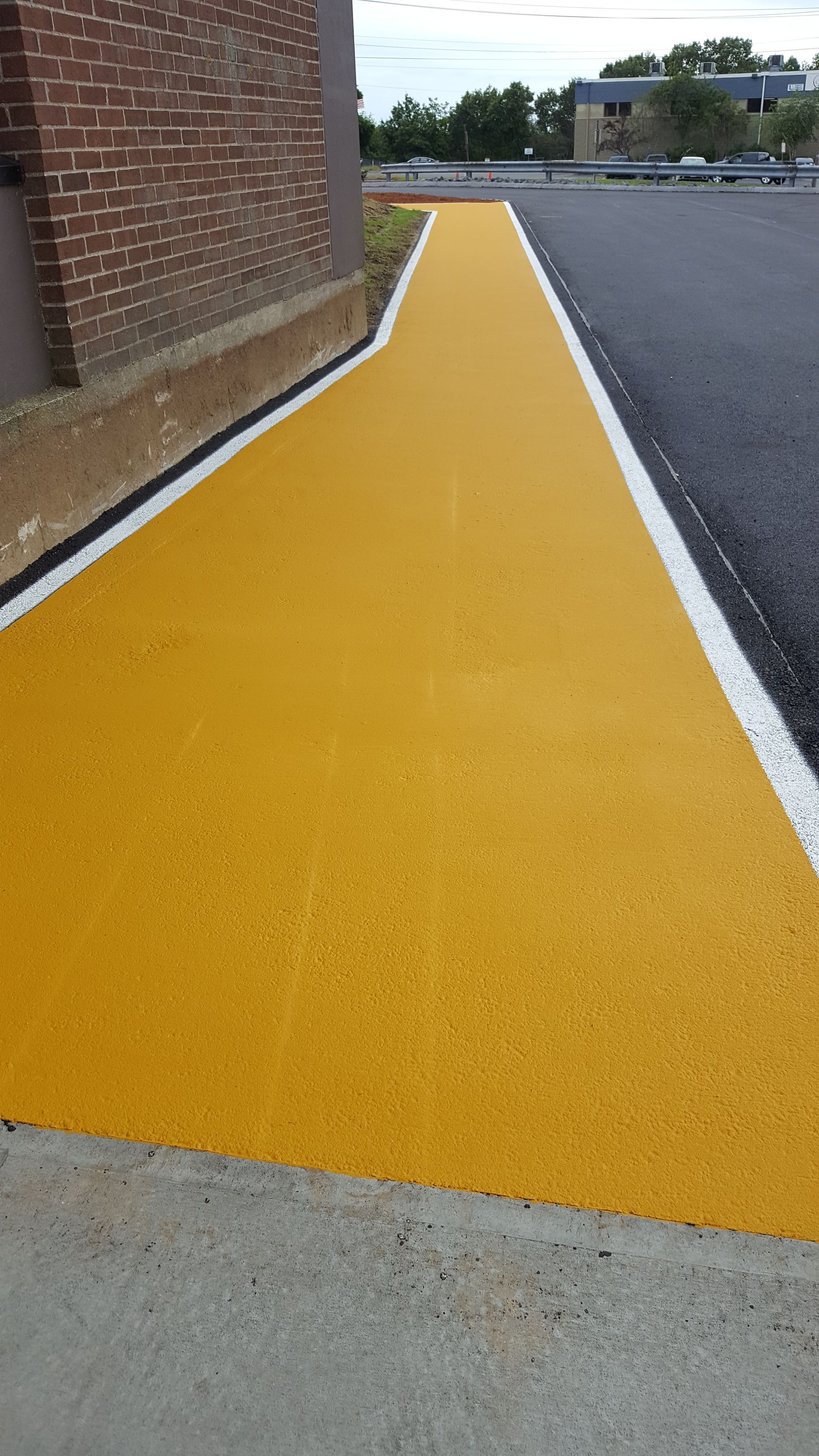 A yellow walkway is painted on the side of a road.