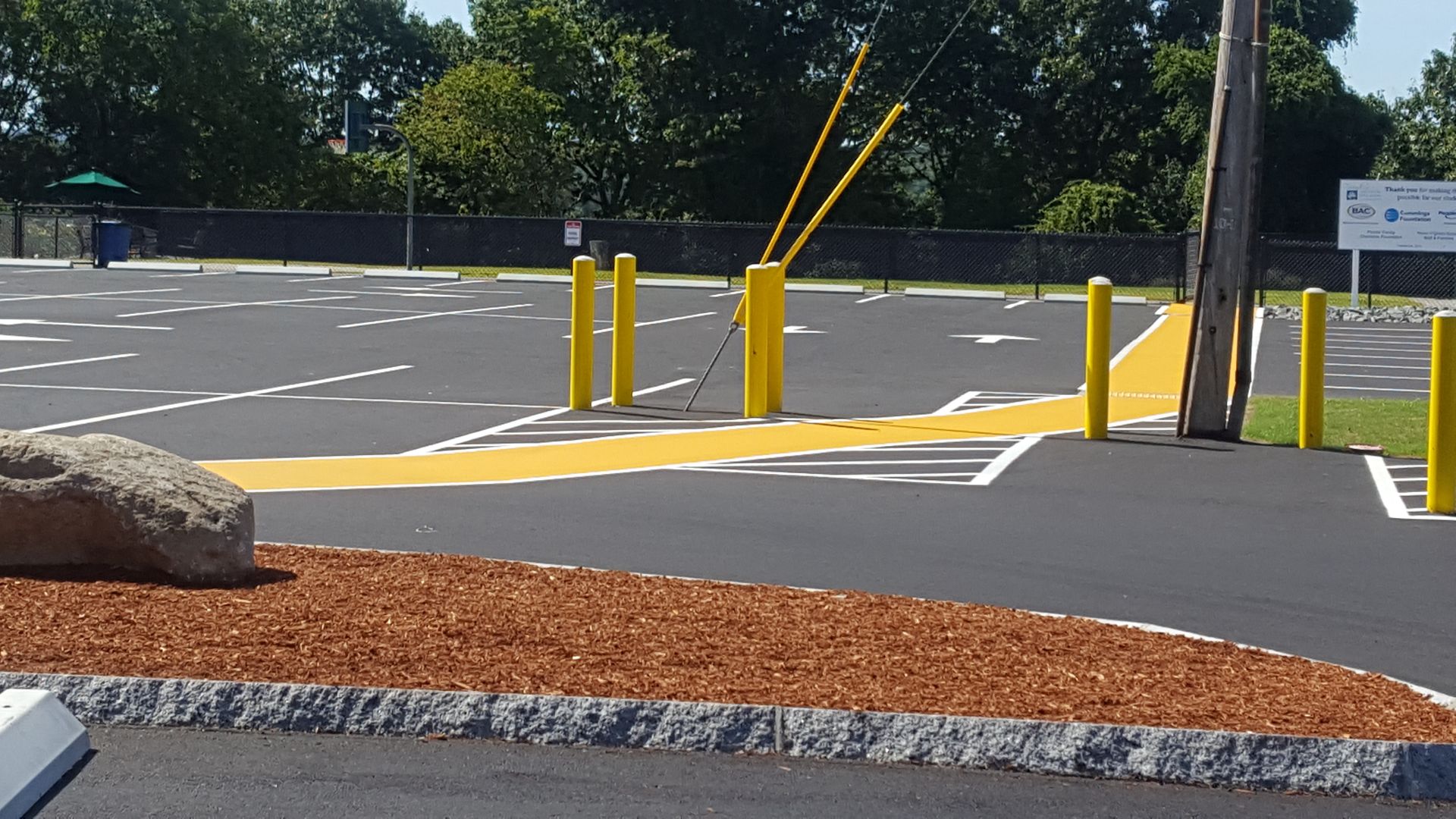 A parking lot with yellow poles and a rock in the middle