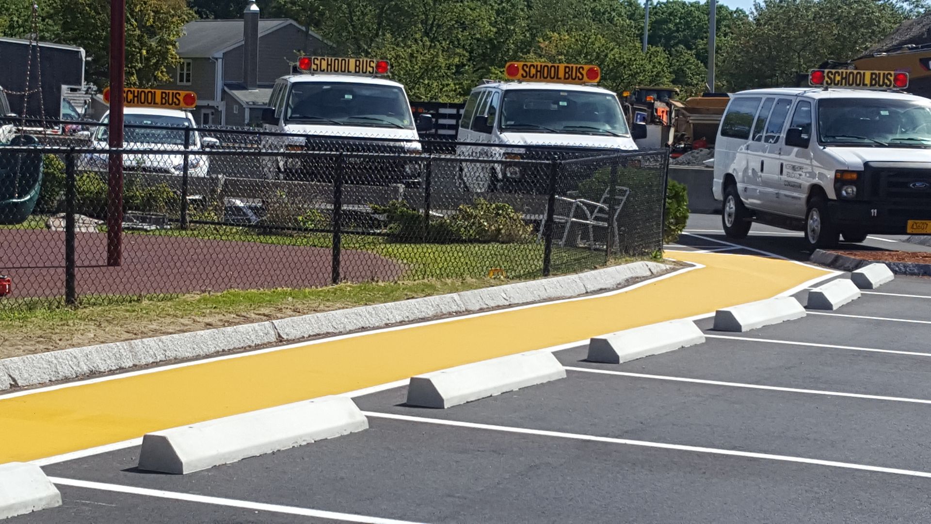 A row of white vans are parked in a parking lot