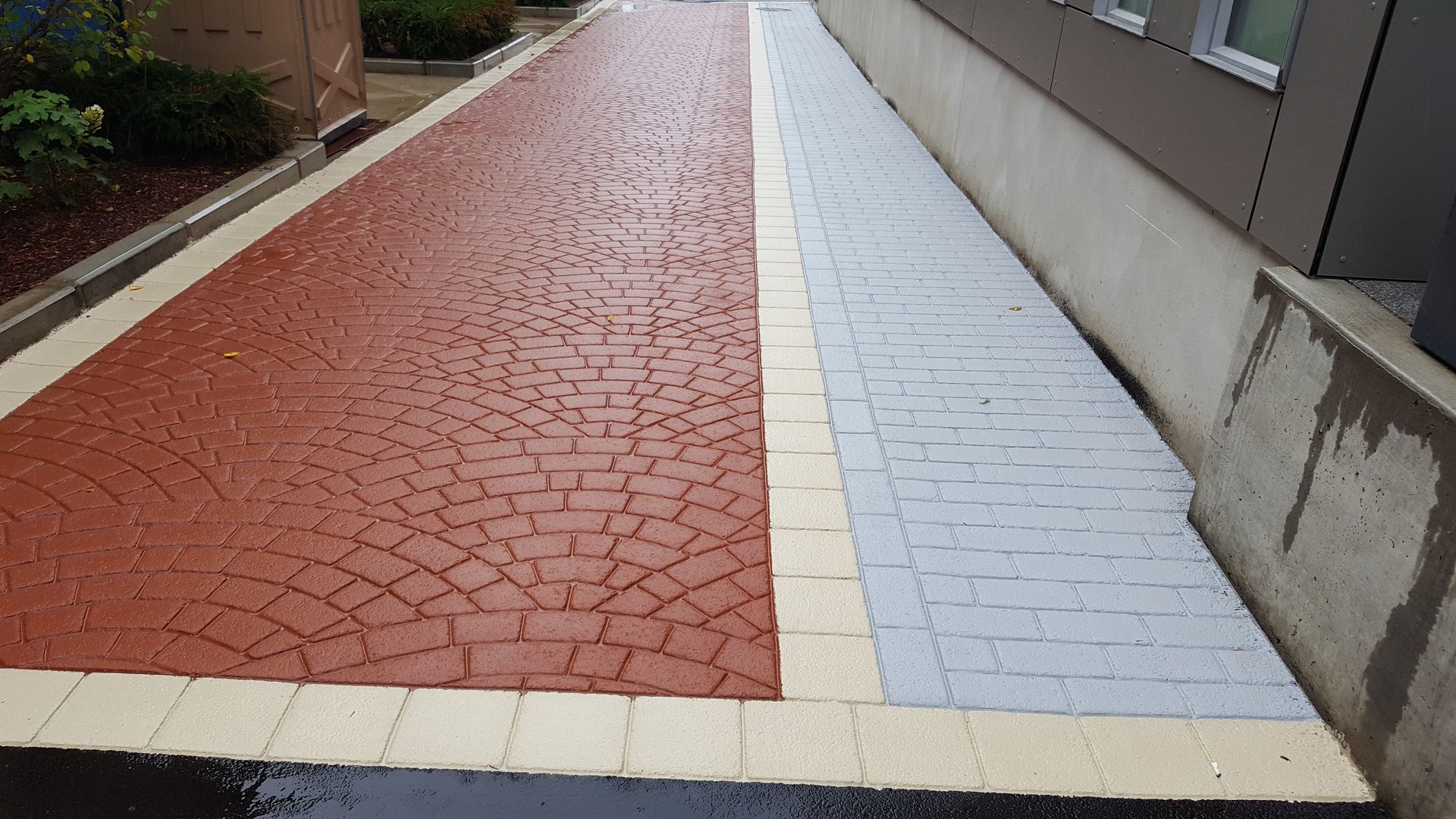 A red and white brick walkway next to a building.