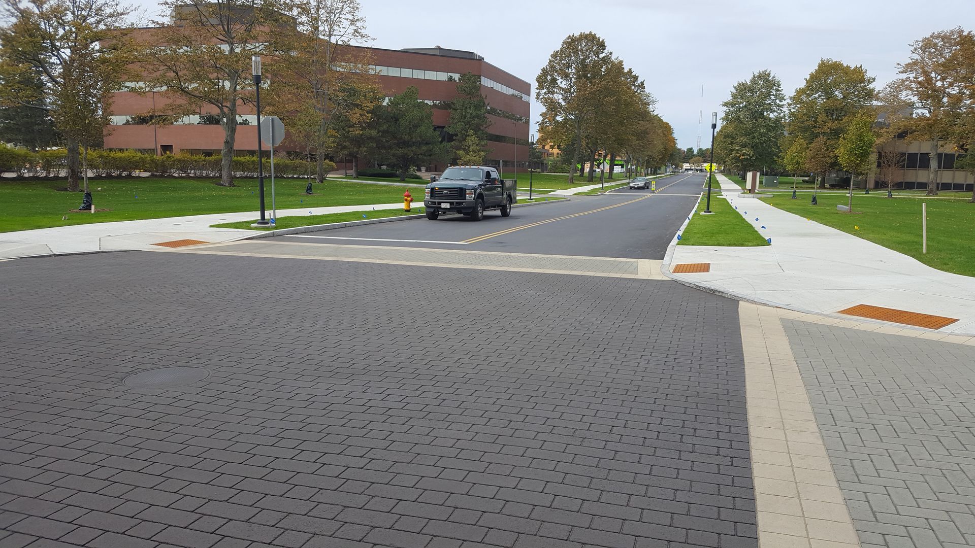 A black truck is driving down a street in front of a large building