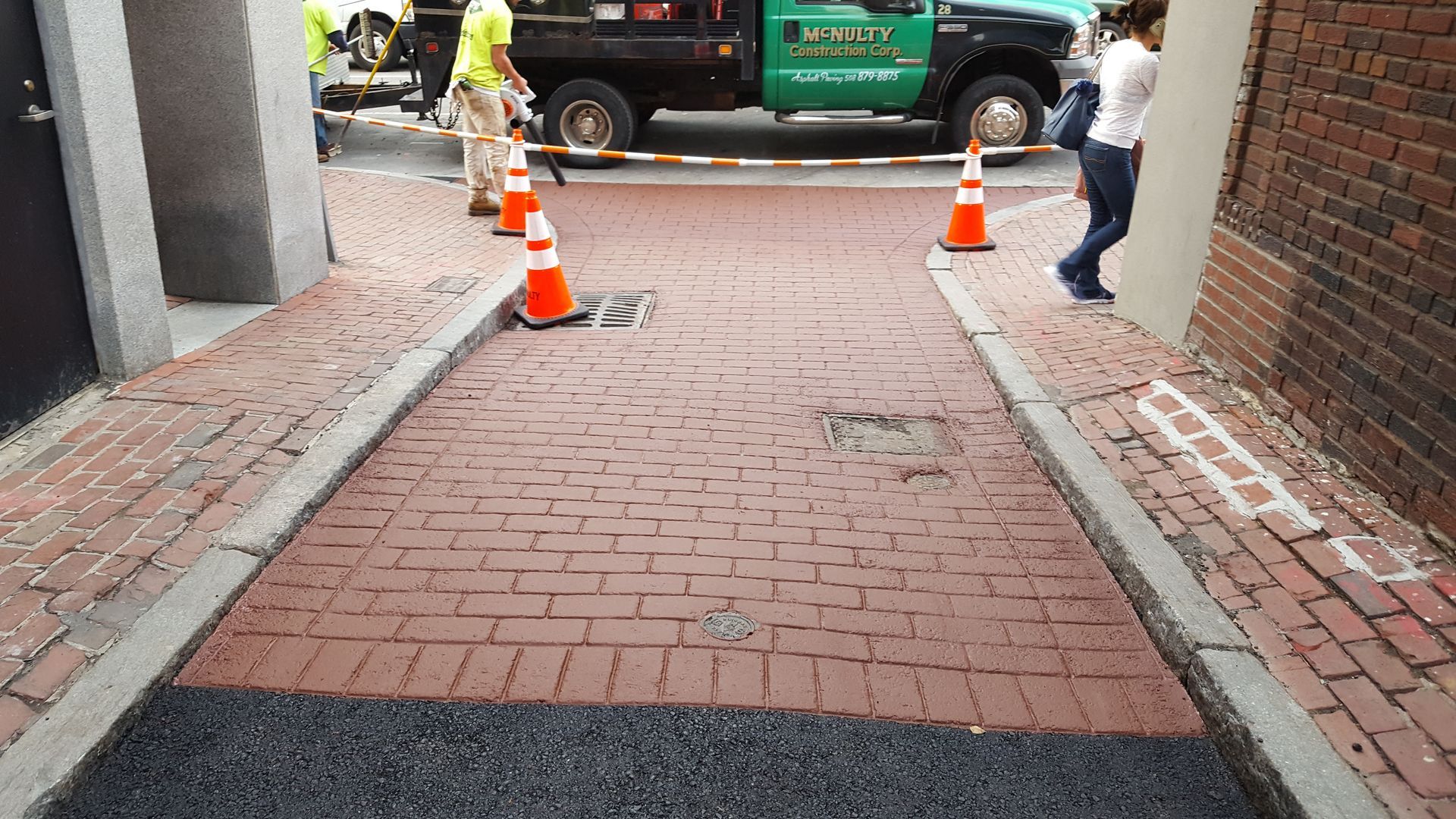 A man is walking down a brick sidewalk next to a truck.