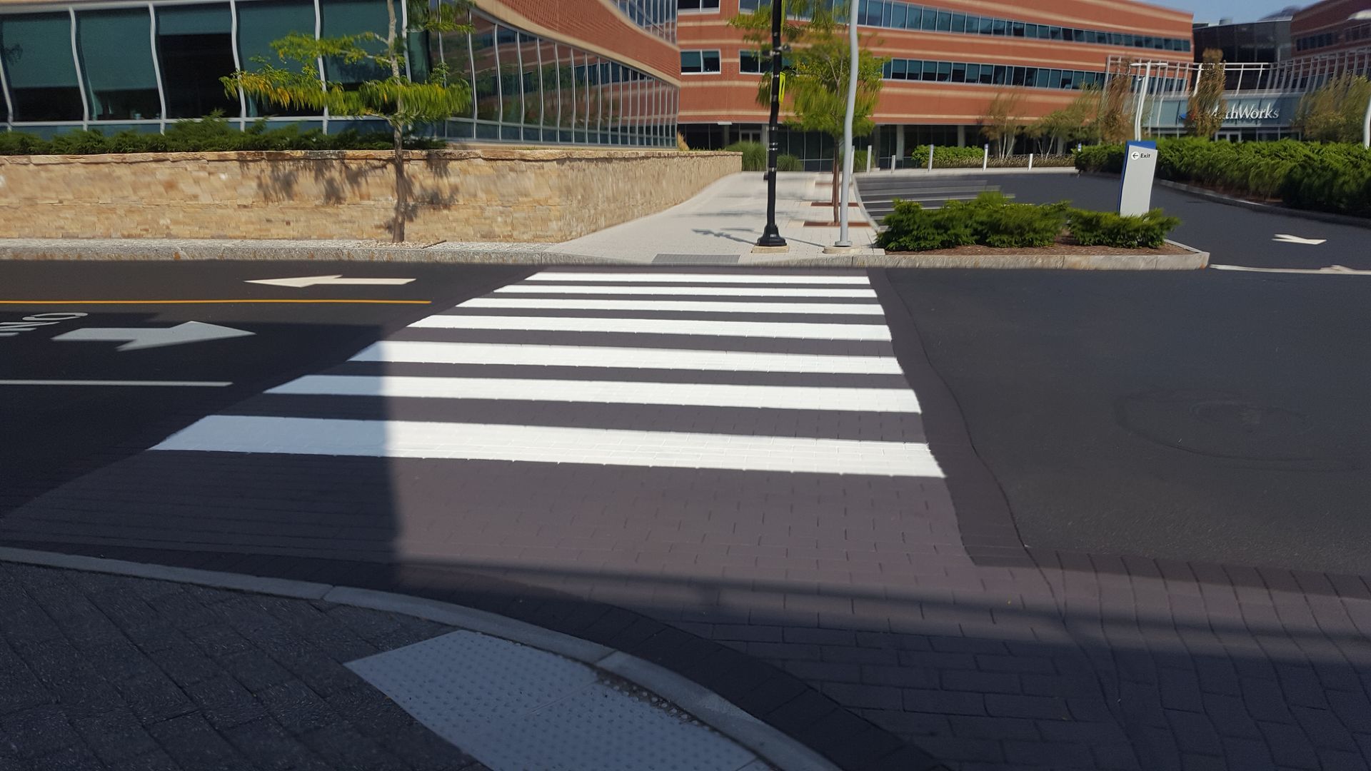 A crosswalk is painted on the side of the road in front of a large building.