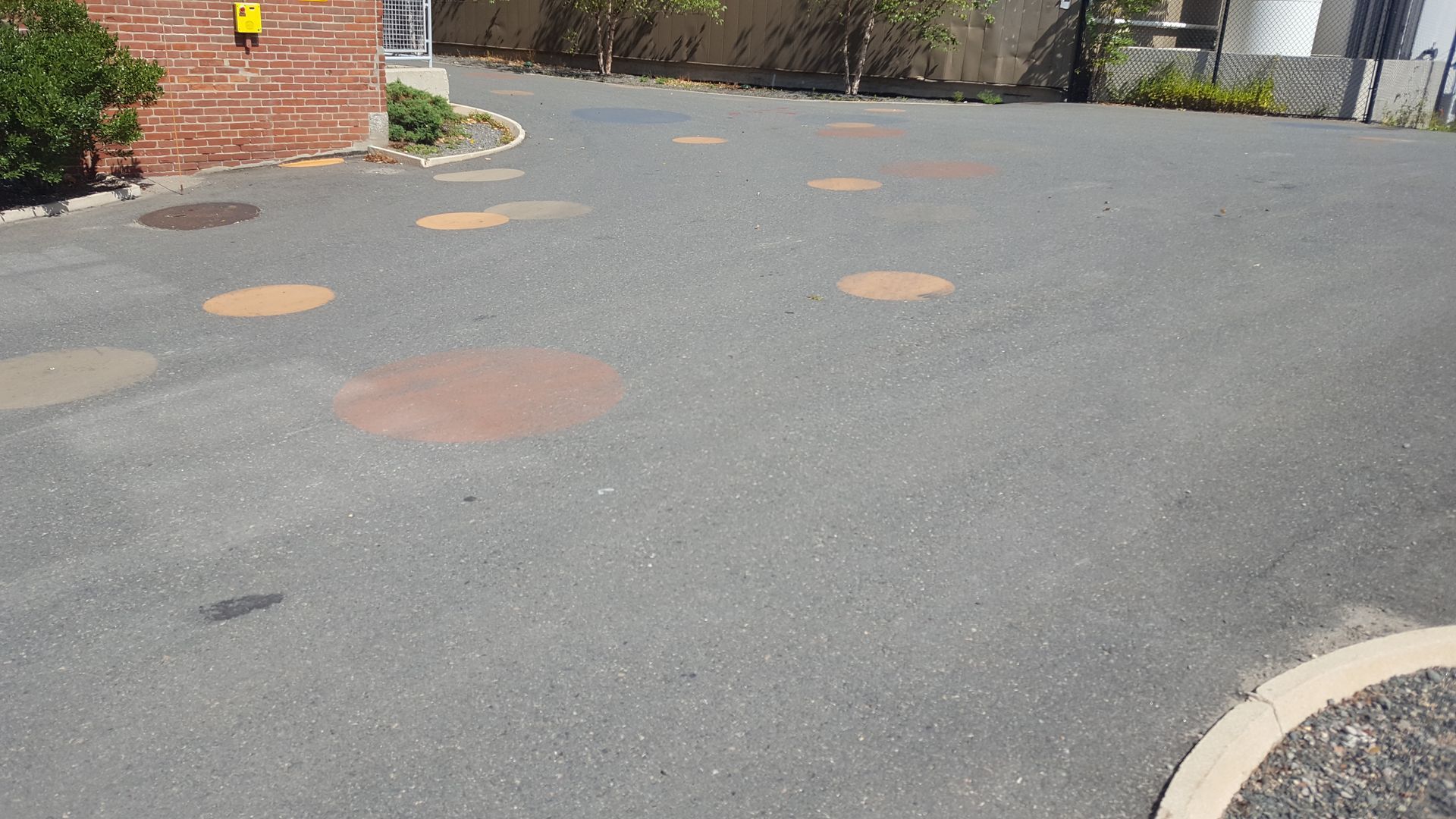 A parking lot with circles painted on the ground and a brick building in the background.