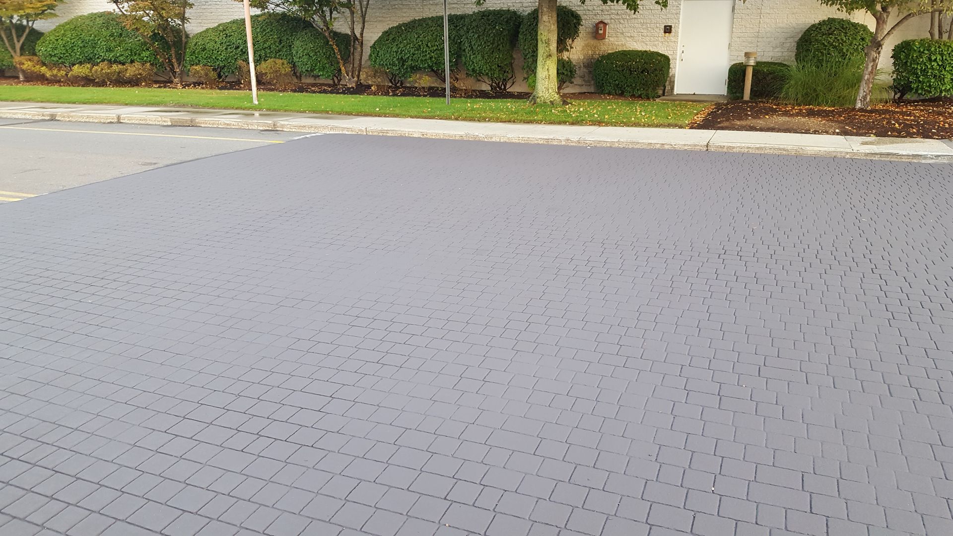 A gray brick driveway with a white house in the background.