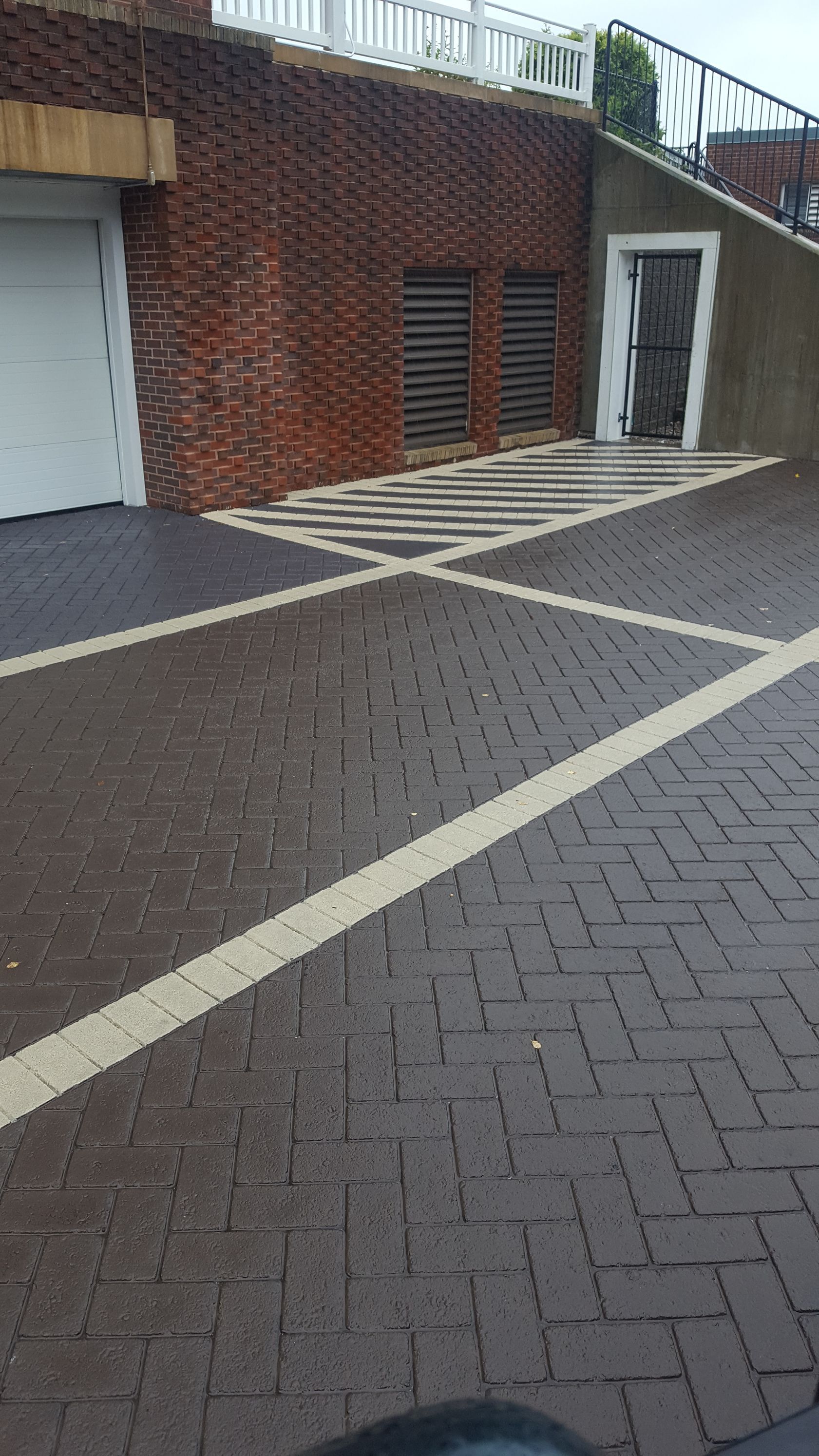A parking lot with a brick wall and a white door.
