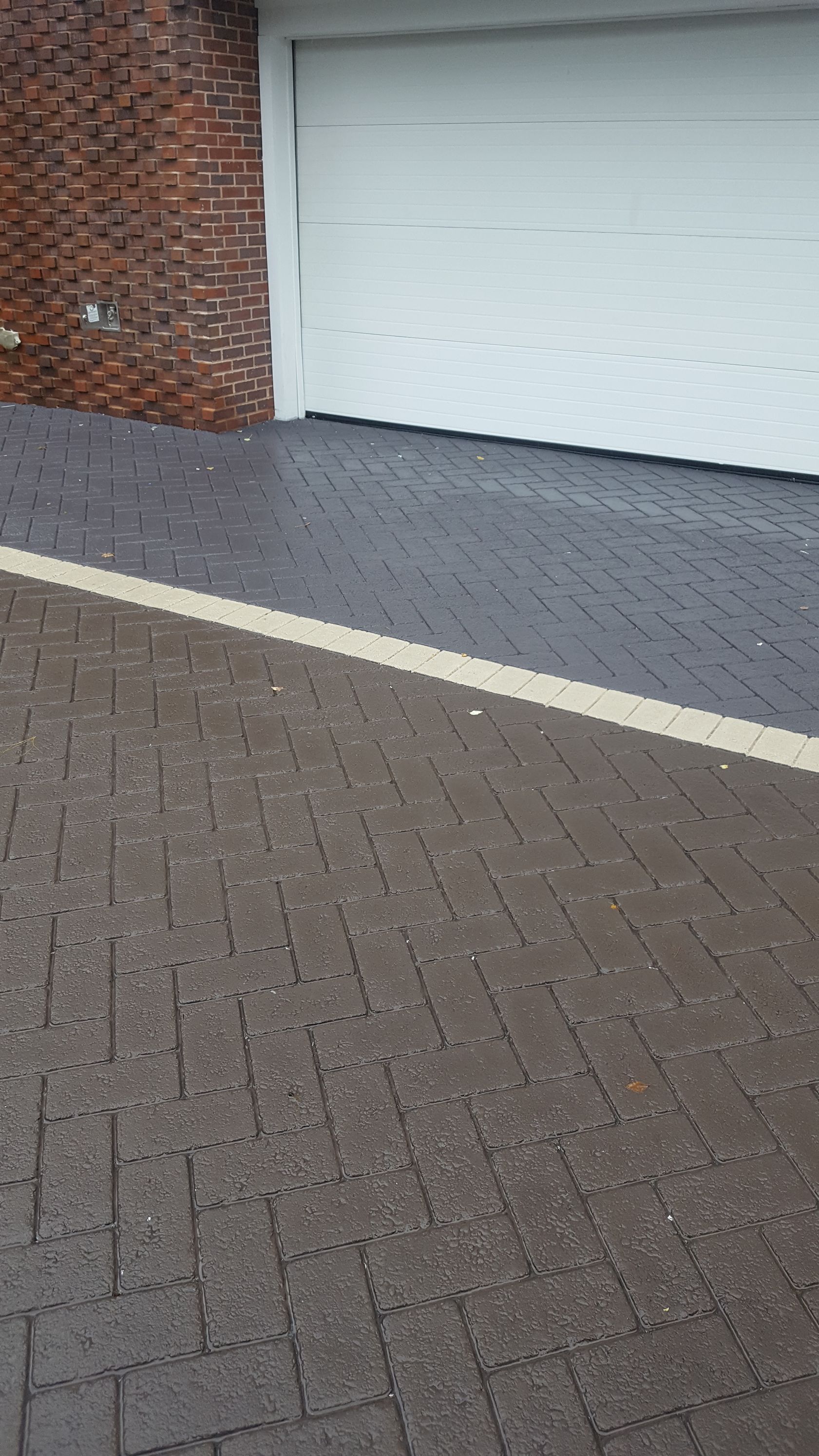 A brick driveway next to a garage with a white garage door.