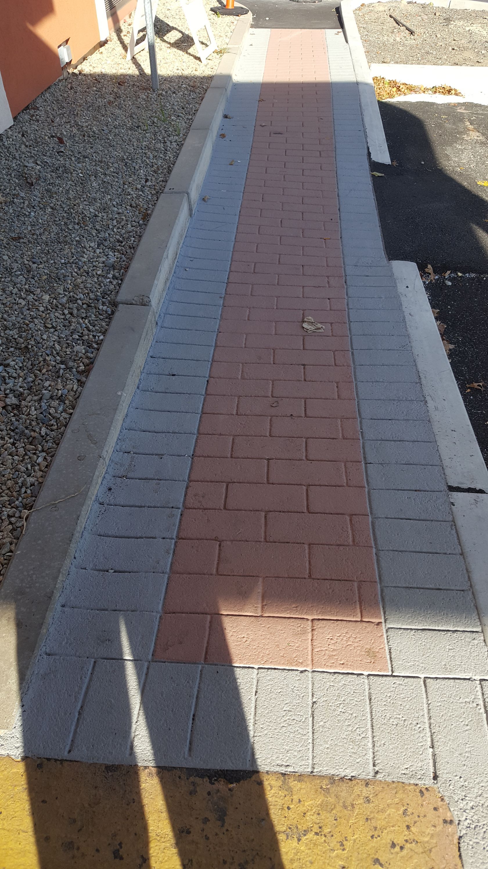 A brick walkway with a shadow of a person on it