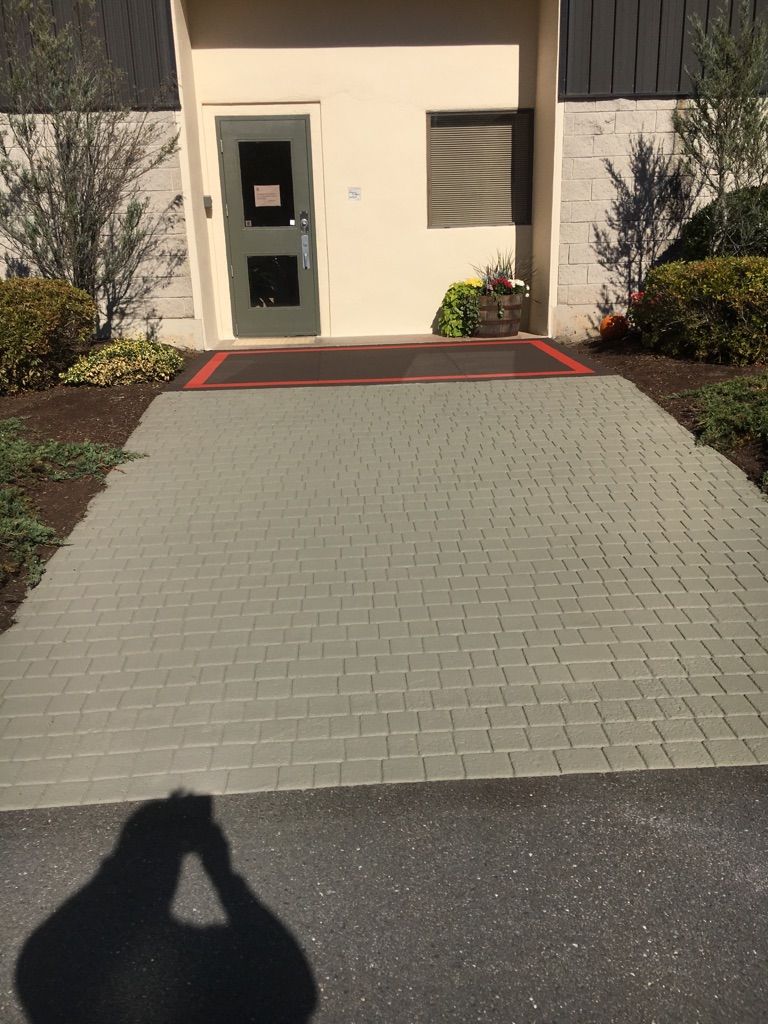 A person is taking a picture of a brick driveway leading to a building.