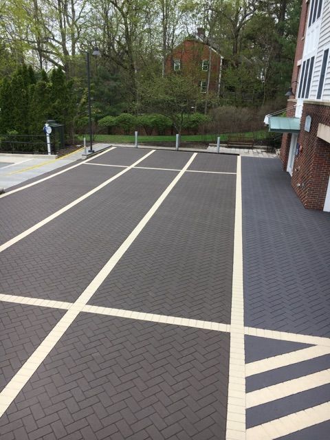 A brick driveway with white lines and a house in the background