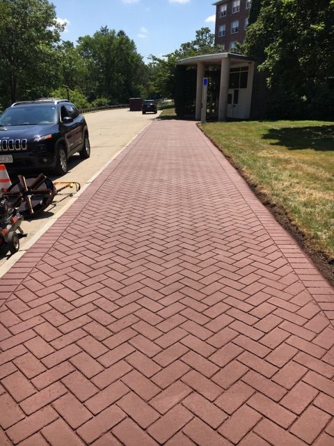 A jeep is parked on the side of a brick driveway