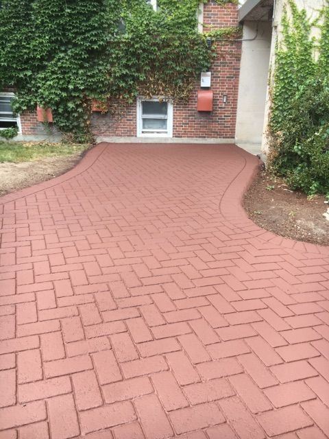 A red brick driveway leading to a brick building
