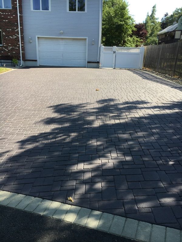 A brick driveway leading to a house with a white garage door