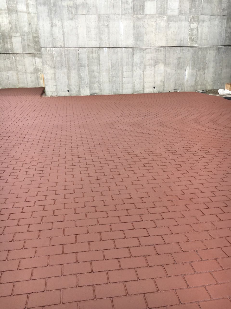 A brick floor with a concrete wall in the background