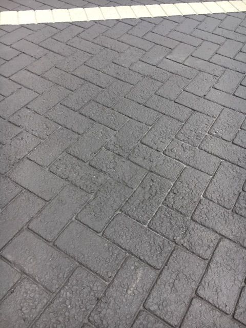 A close up of a brick driveway with a white line in the middle.